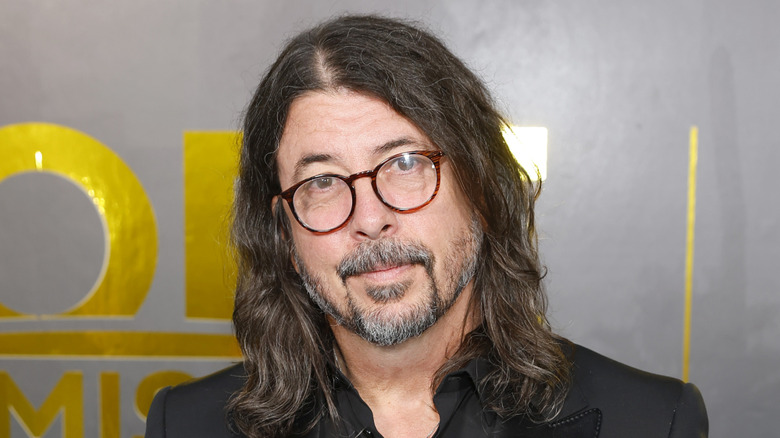 Dave Grohl à lunettes, tête baissée devant la caméra