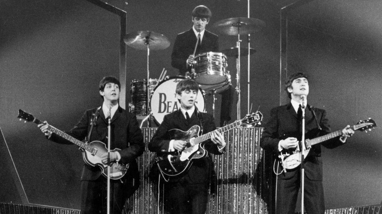Les Beatles en costume jouant sur scène