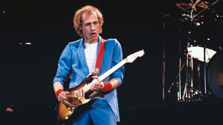 Mark Knopfler sur scène en costume bleu avec guitare