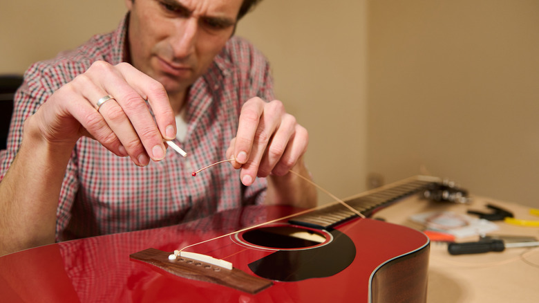 Homme retendant la guitare rouge