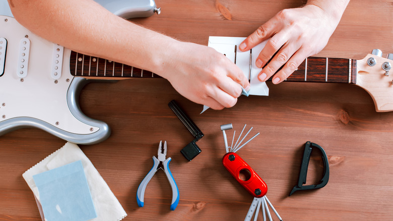 Personne nettoyant la guitare avec un kit de nettoyage