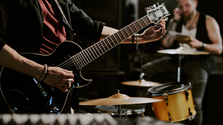 Musicien accordant une guitare électrique avec un groupe