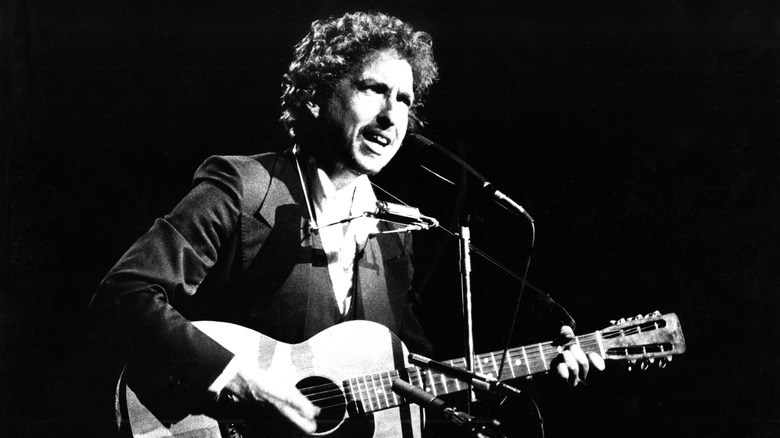 Bob Dylan joue de la guitare et chante