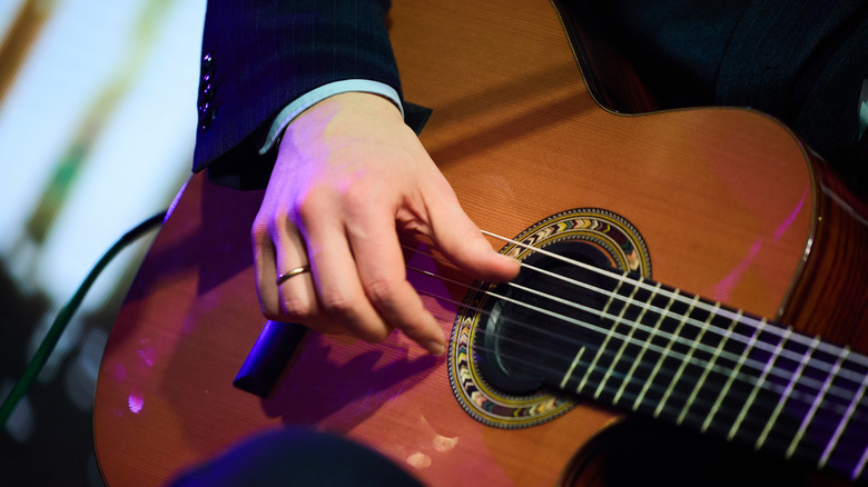 Un gros plan des mains de quelqu'un jouant de la guitare acoustique.