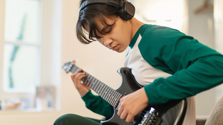 Un jeune homme jouant de la guitare avec des écouteurs