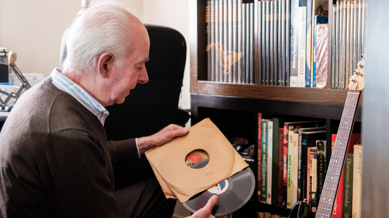 Un homme âgé admirant sa collection de disques vinyles.