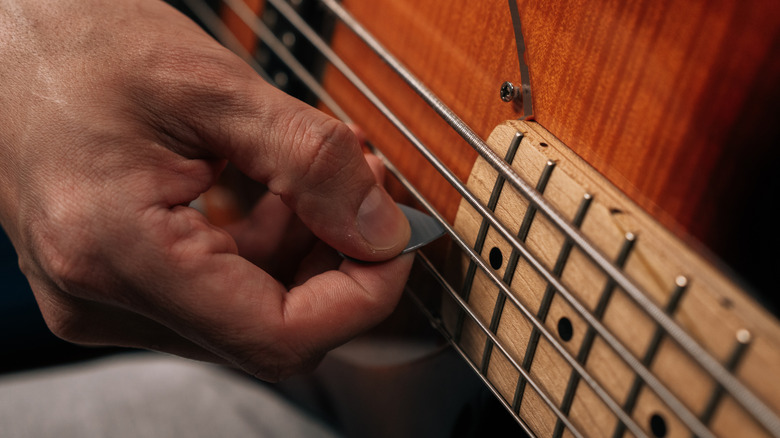 Gros plan d'une main tenant un médiator de guitare.