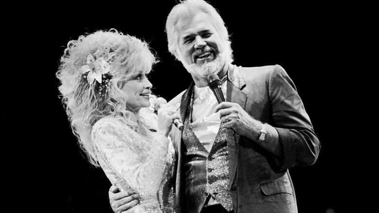 Photo en noir et blanc de Kenny Rogers et Dolly Parton des années 1980, se produisant sur scène