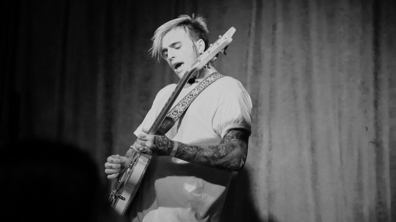 Photo en noir et blanc de Johnny Stevens de Highly Suspect jouant de la guitare lors d'un concert en 2015