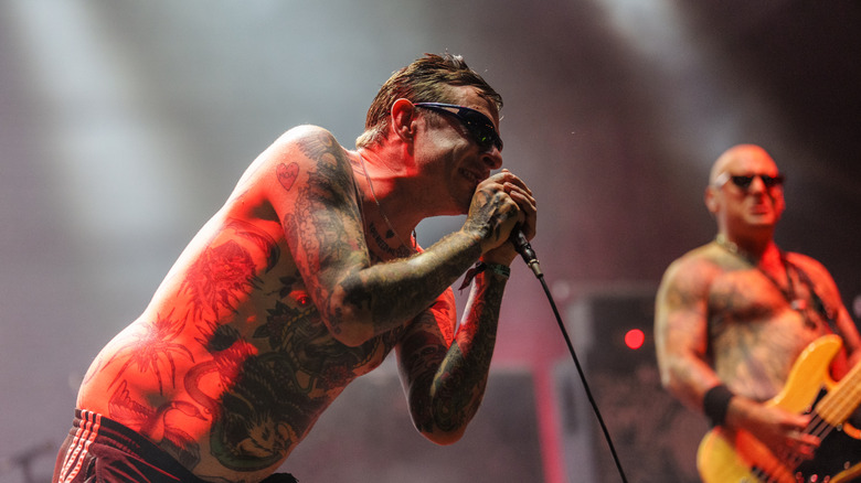 Sebastian Murphy des Viagra Boys penché sur un microphone avec des lumières rouges s'illuminant derrière lui lors de son set Lollapalooza en 2026