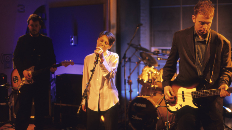 Cocteau Twins alignés sur scène avec un éclairage orange et violet pendant leur représentation