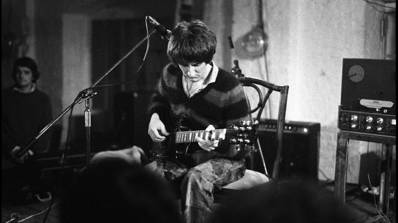 Photo en noir et blanc de Vini Reilly jouant de la guitare sur scène dans les années 80