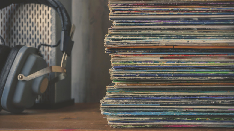 pile de vieux vinyles à côté d’une paire d’écouteurs